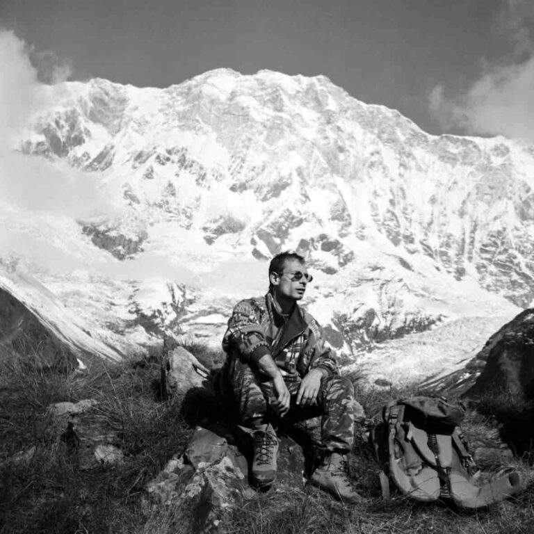 randonneur assis devant des montagnes enneigées