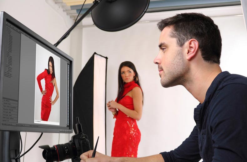 homme retouchant une photo sur ordinateur avec le modèle en roibe rouge en arrière plan