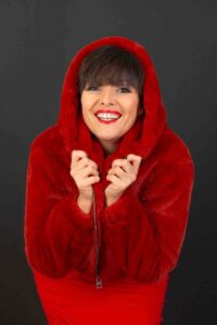 Photo de portrait en studio à Agen, femme souriante resserrant sa capuche en fourrure rouge