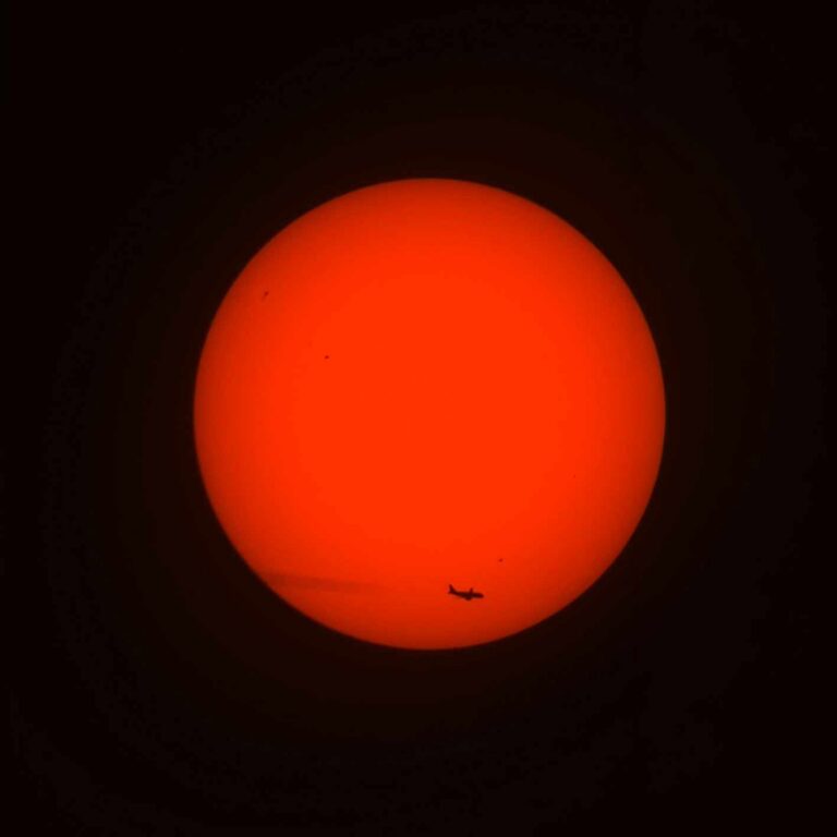 Silhouette d'un avion en transit devant le disque solaire, photographié au télescope